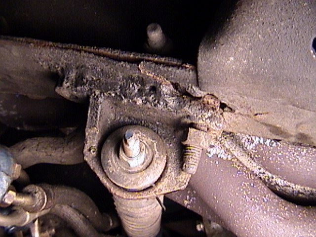 Rusty undercarriage view of a suspension mount bracket with threaded stud and bolts on a 1968 Ford Mustang
