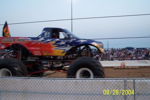1979 Ford Bronco II - A monster truck with a patriotic stars and stripes paint scheme is captured in motion during an event.
