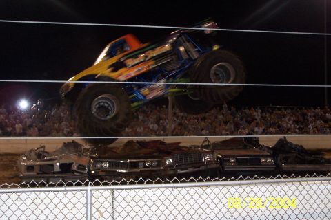 1979 Ford Bronco II - Monster truck event with a large crowd watching as cars are crushed.