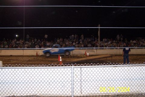 1979 Ford Bronco II - A blue pickup truck competes on a dirt track in front of a large audience.