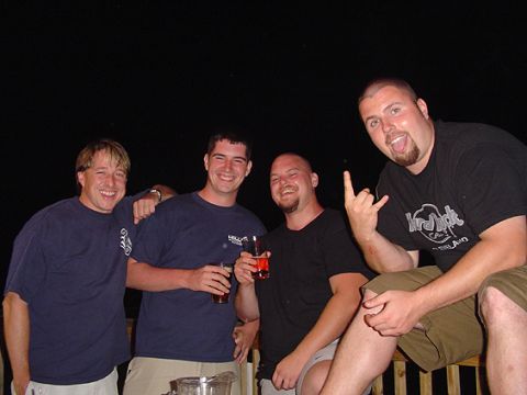 1979 Ford Bronco - Four men pose together outdoors at night on a wooden deck, holding drinks; one wears a Hard Rock Cafe t-shirt and throws devil horns. No ve…