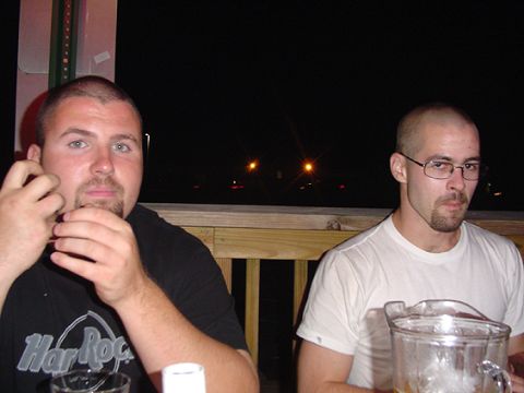 1979 Ford Bronco - Two men sit at a wooden patio rail at night, one in a black Hard Rock t-shirt and one in a white tee, with a nearly empty beer pitcher on t…