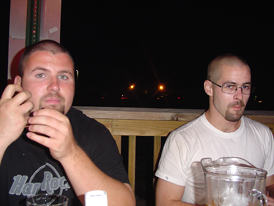Two men at a night patio table with an empty beer pitcher