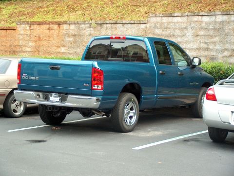 1998 Ford Taurus - A teal Dodge Ram pickup truck is parked in a lot, showing its rear and side profile. The truck has a SLT badge.