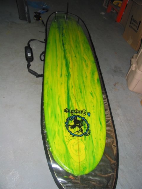 1992 Ford Bronco - A surfboard with a marbled yellow and green design and a 'Sunshine' logo is placed inside a protective bag.