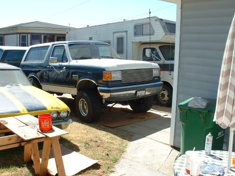 1990 Ford Bronco - This lifted 1990 Ford Bronco is parked next to a yellow car and an RV.
