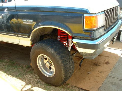 1990 Ford Bronco - Close-up of the front wheel and suspension system of a Ford Bronco, highlighting its lifted stance.