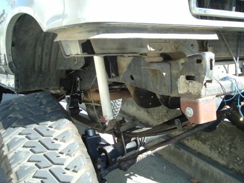 1989 Ford Bronco - Front suspension and tire detail of a modified truck, likely undergoing modifications.