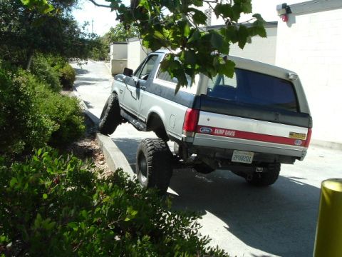 1989 Ford Bronco - This modified Ford Bronco is shown with its front wheels on a curb, demonstrating its off-road capabilities.
