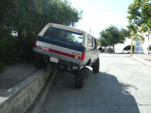 1989 Ford Bronco - This 1989 Ford Bronco is seen performing a flex test on a concrete barrier, demonstrating its suspension capabilities.
