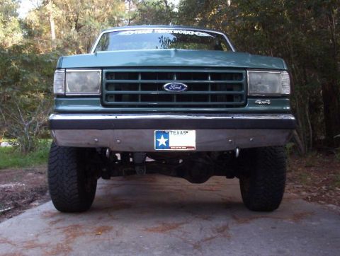 1989 Ford Bronco - Front view of a green Ford truck with a lifted suspension and a Texas license plate.
