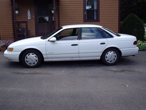 1998 Ford Taurus - Side view of a white 1998 Ford Taurus sedan parked in a driveway.