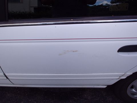1998 Ford Taurus - This photo shows the side of a white sedan, focusing on the rear door and its condition.