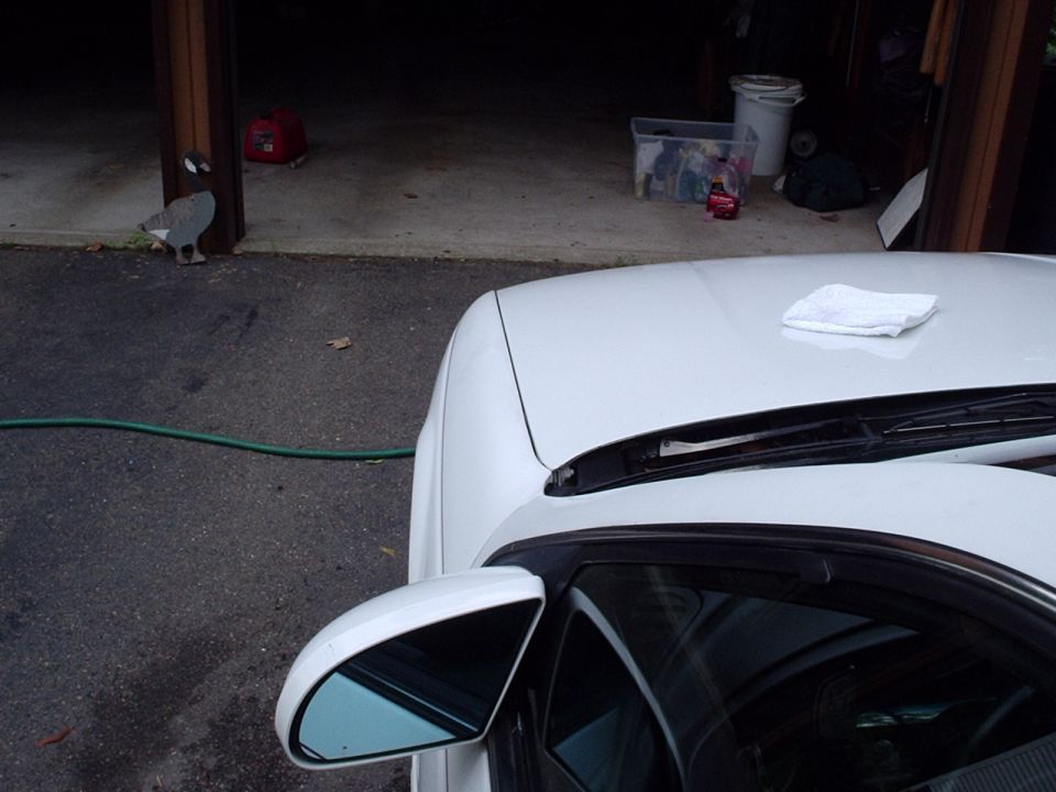 White car hood with a folded cloth and side mirror. Garage interior visible in background