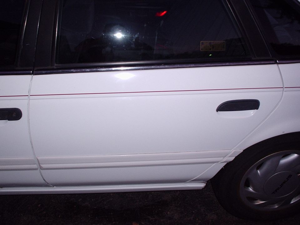 White sedan side view, showing door handles and wheel cover with 'TAURUS' text