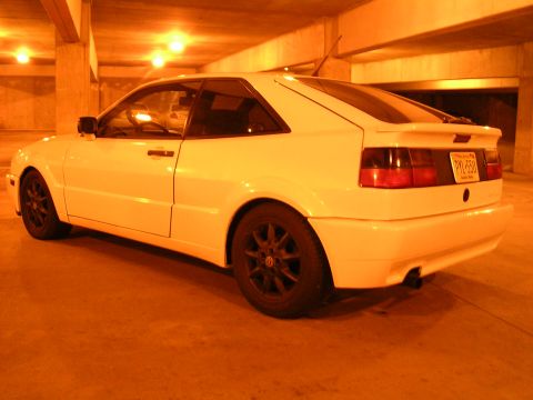 1990 Volkswagen Corrado - A white 1990 Volkswagen Corrado is parked in a dimly lit garage, its distinctive rear design and black aftermarket wheels.