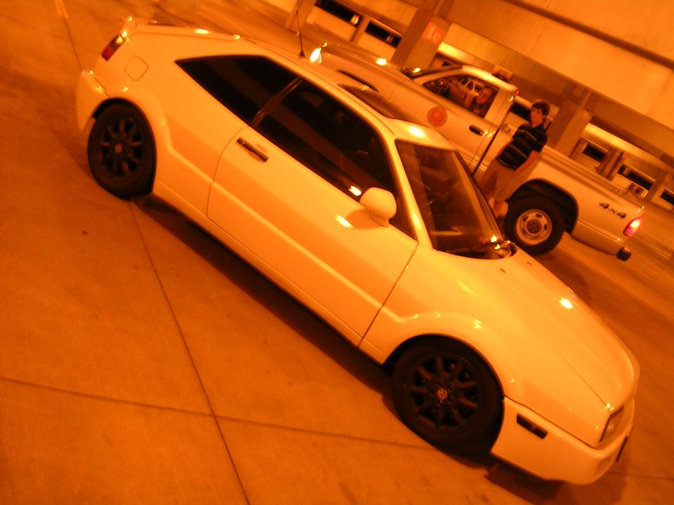 White VW Corrado lowered on black wheels at night under amber light