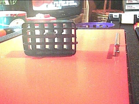 1992 Ford F-150 - A black plastic vent with a grid pattern is shown on an orange surface, with a metal object to its right.