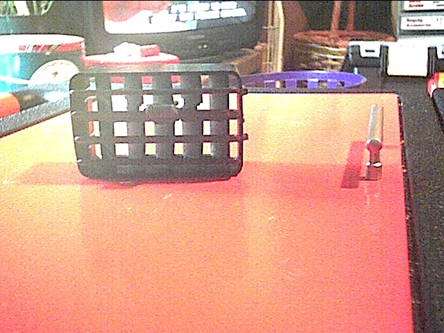 Black plastic vent with square openings on an orange surface