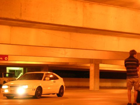 1990 Volkswagen Corrado - A white 1990 Volkswagen Corrado is parked in a garage, its headlights illuminating the scene.