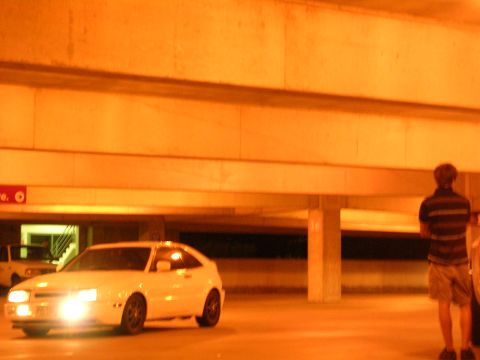 1990 Volkswagen Corrado - A white coupe sits in a dimly lit parking garage with its headlights illuminated.