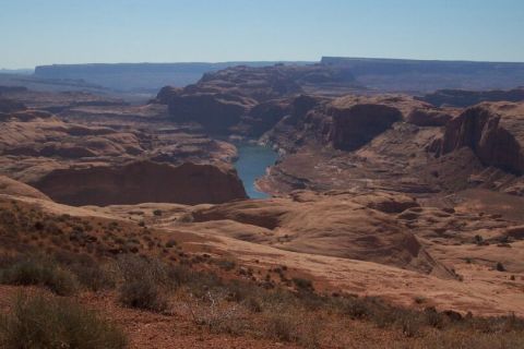 1990 Ford Bronco - A vast canyon landscape unfolds with a winding river carving through red rock formations under a bright blue sky.