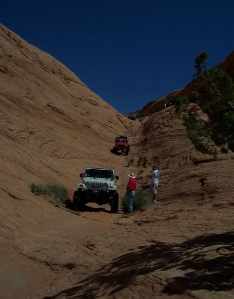 1990 Ford Bronco - Multiple Jeeps ascend a challenging rocky incline on an off-road trail.