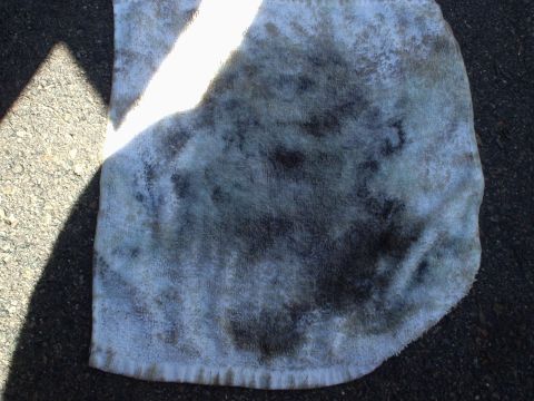 1998 Ford Taurus - A towel stained with oil lies on asphalt, with a shadow cast from the left.