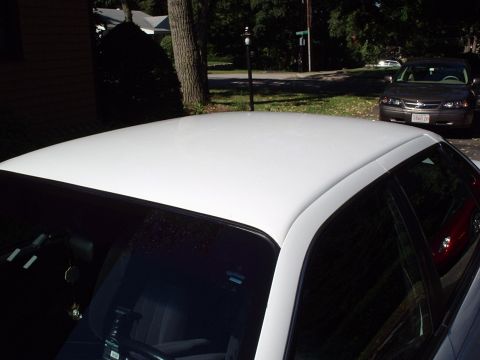1998 Ford Taurus - The photo shows the roof of a white car, with another vehicle parked in the background on a residential street.
