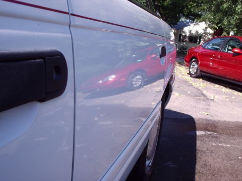 1998 Ford Taurus - Reflection of a red car is visible on the side of a white van.