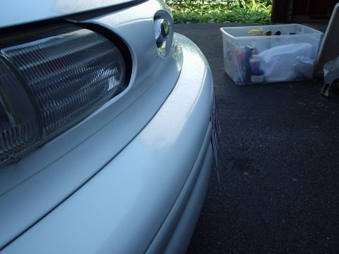 1998 Ford Taurus - The front corner of a white sedan is visible, with a clear storage bin in the background.