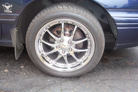 1993 Ford Taurus - Close-up of a custom chrome wheel and tire on a vehicle. A TCCA logo is visible on the fender.