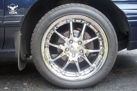 1993 Ford Taurus - A close-up shot focuses on the custom chrome wheel and tire, with a mud flap visible behind it.