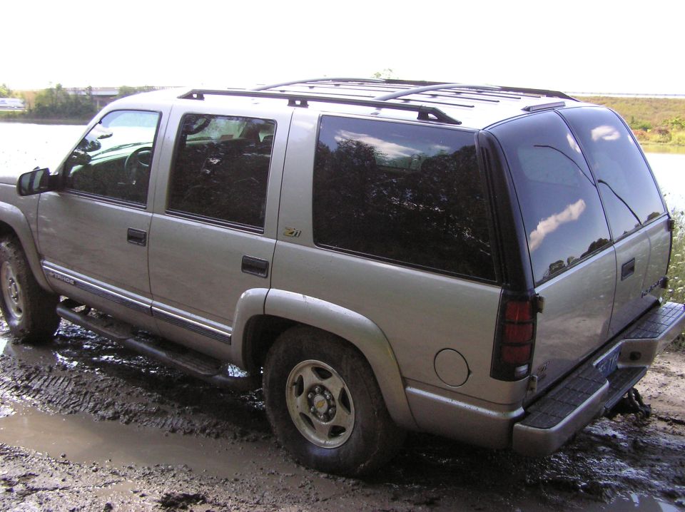 Silver SUV stuck in mud, rear quarter view. Looks like a late 90s model