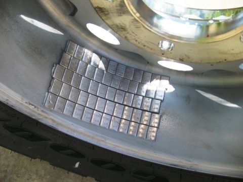 1985 Ford Bronco - A close-up view of numerous adhesive wheel weights attached to the inside of a vehicle's wheel rim.