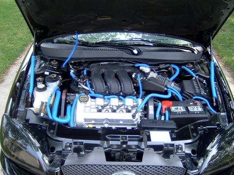 2004 Ford Taurus - The engine bay of a 2004 Ford Taurus features a V6 engine with custom blue hoses and a black engine cover.