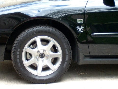 2004 Ford Taurus - Close-up of a black car's front fender and wheel, showing a '24V DOHC TCCA' badge.