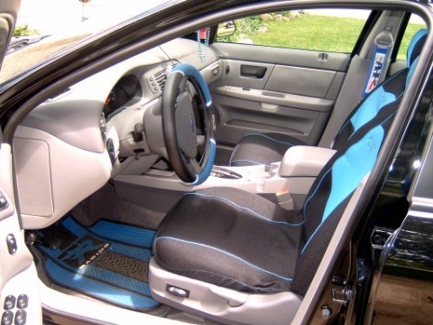 2004 Ford Taurus - The interior of a car features custom seat covers and floor mats with a blue and black design.