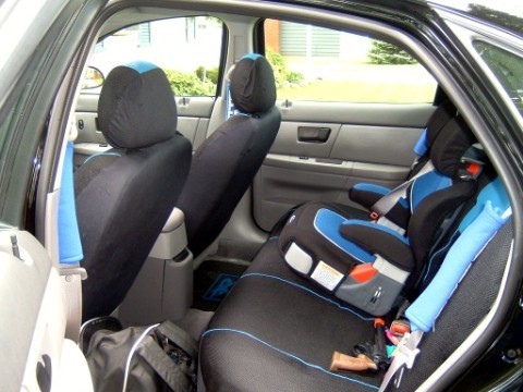2004 Ford Taurus - The interior of a car is shown, including front seats with covers and a child car seat installed in the rear.