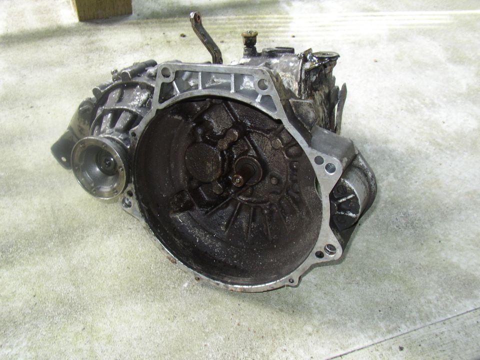 Greasy transaxle/transmission case standing on concrete, bellhousing facing camera
