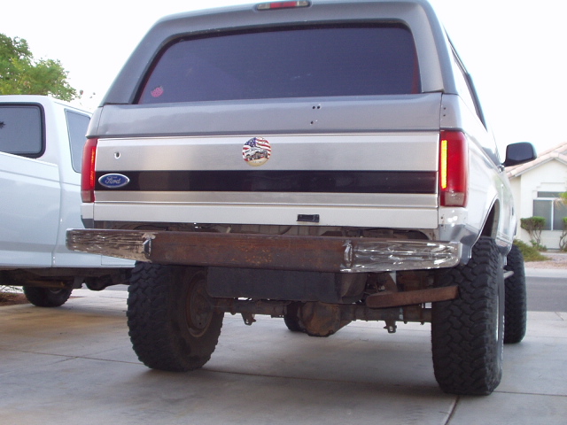 Rear of silver Ford Bronco with chrome bumper and mud tires in a driveway