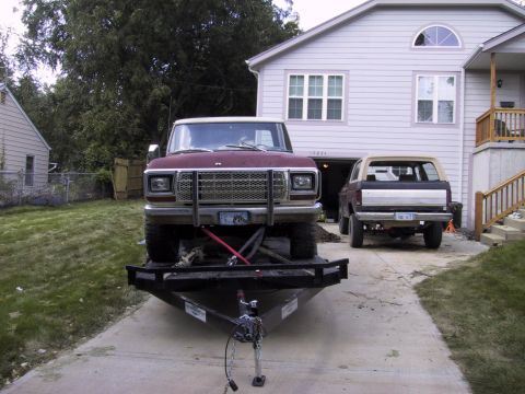 1983 Ford Bronco - Two Ford Broncos are parked in a driveway, one on a trailer in front.