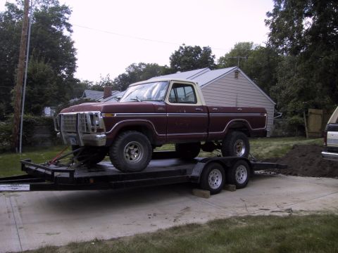 1983 Ford Bronco - This pickup truck is on a trailer in front of a house. Another vehicle is partially visible to the right.