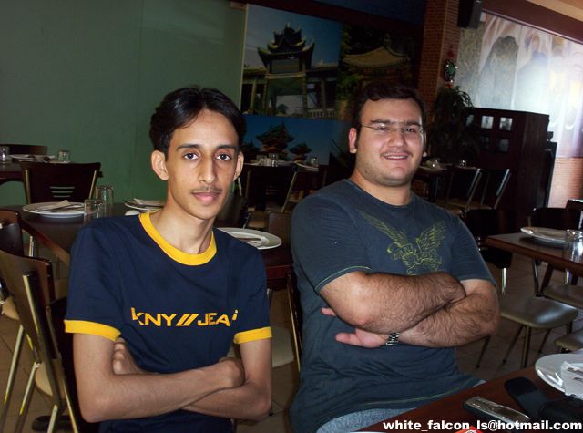 Two men in a restaurant, one wearing a navy shirt with yellow trim