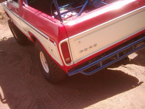 1978 Ford Bronco - Rear view of a red and white 1978 Ford Bronco, modified with a roll cage and aftermarket bumper.