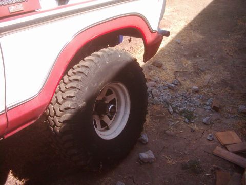 1978 Ford Bronco - A 1978 Ford Bronco is viewed from the side, highlighting its off-road tire and red fender trim.