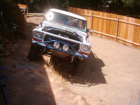 1978 Ford Bronco - Modified 1978 Ford Bronco with roll cage and custom front bumper sits in a dirt lot.