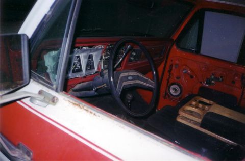 1978 Ford Bronco - The interior of a red and white vehicle is shown, with the dashboard and steering wheel visible.