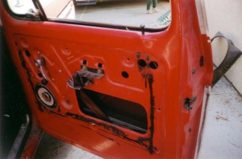 1978 Ford Bronco - The interior of a red car door shows exposed metal and components, suggesting a restoration or repair process.