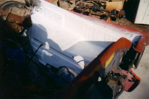 1978 Ford Bronco - A person in a helmet works on the engine bay of a vehicle, which is being prepped for paint.
